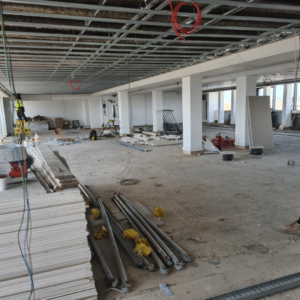 The empty interiors of a building in a “shell” state. Construction materials are stacked to one side in preparation for the next phase of an interior fit out.