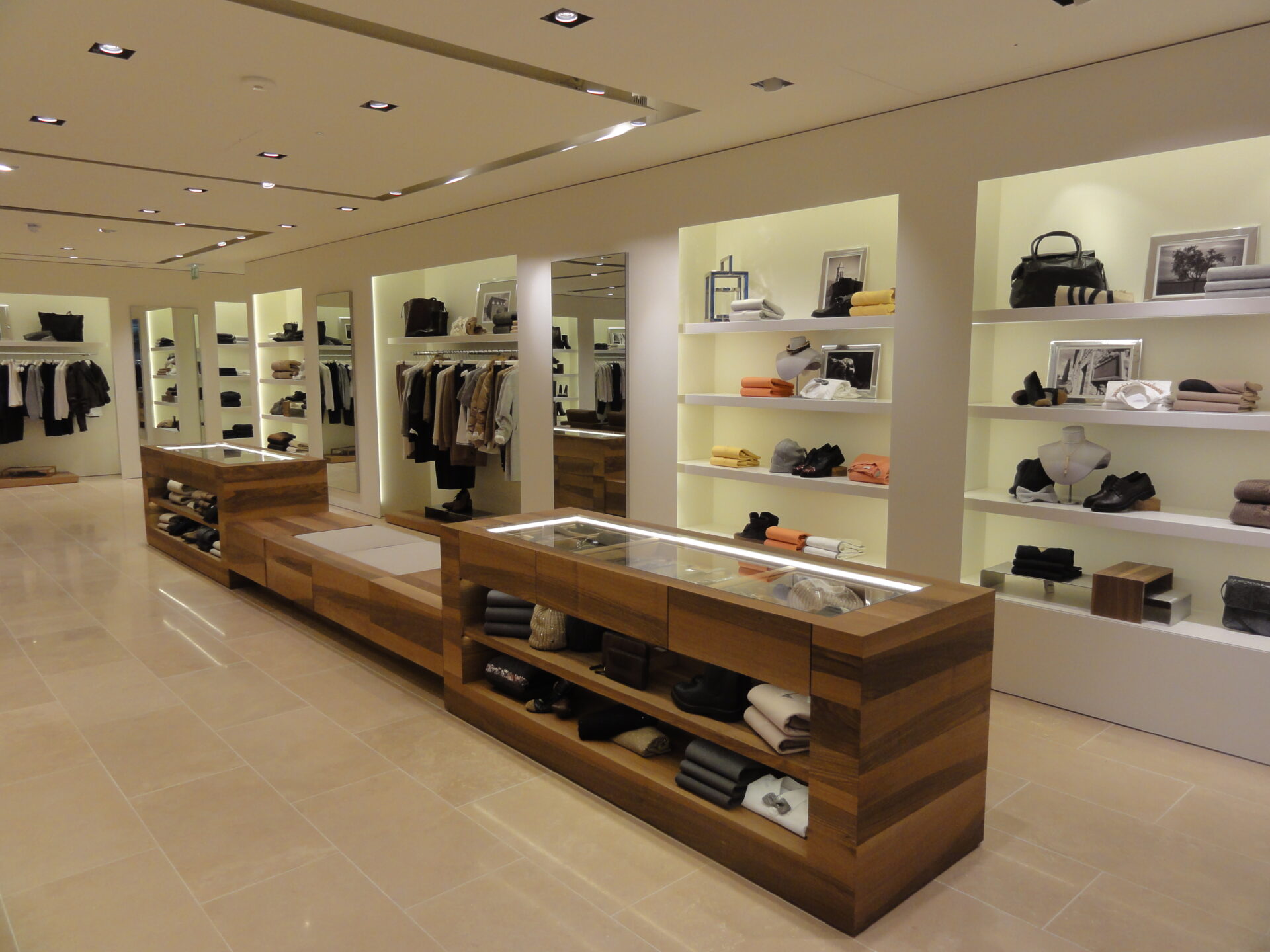 Ultra-modern interiors of the Brunello Cucinelli Mayfair shop. Part of the Cat B fit out involved the installation of bespoke lighting within cabinets to illuminate clothing.