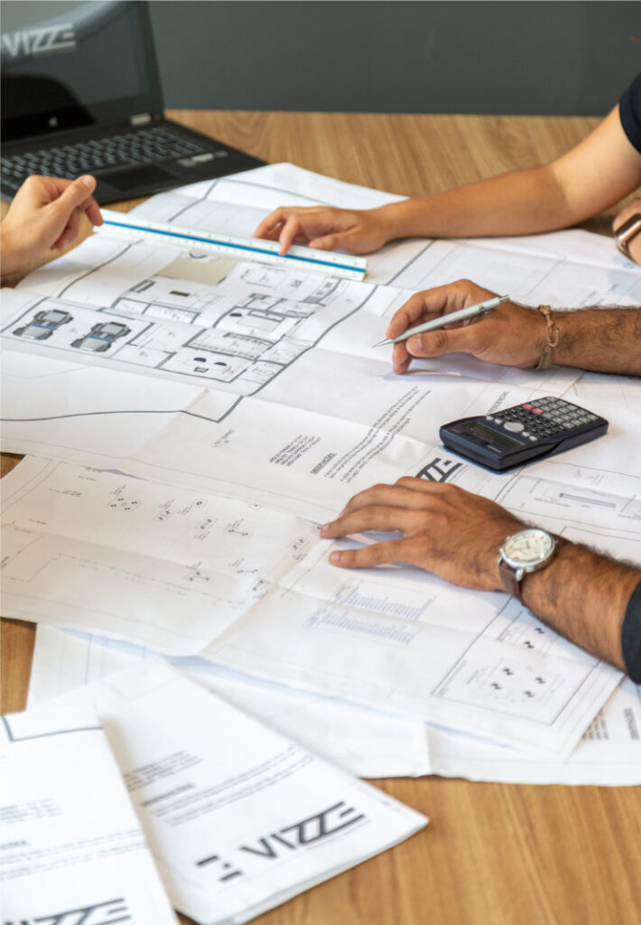 Detailed plans on a table, with people collaborating over next steps