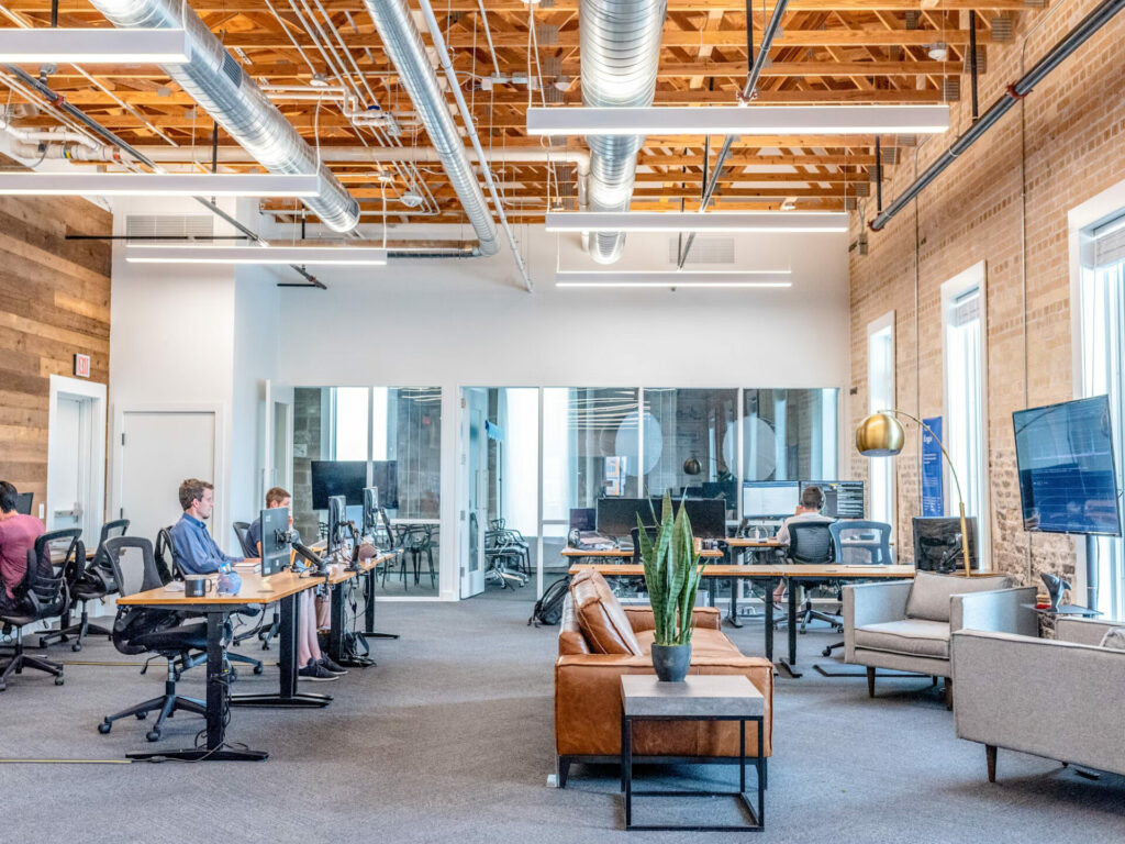 An open plan office with a breakout area and desks and chairs and people at work